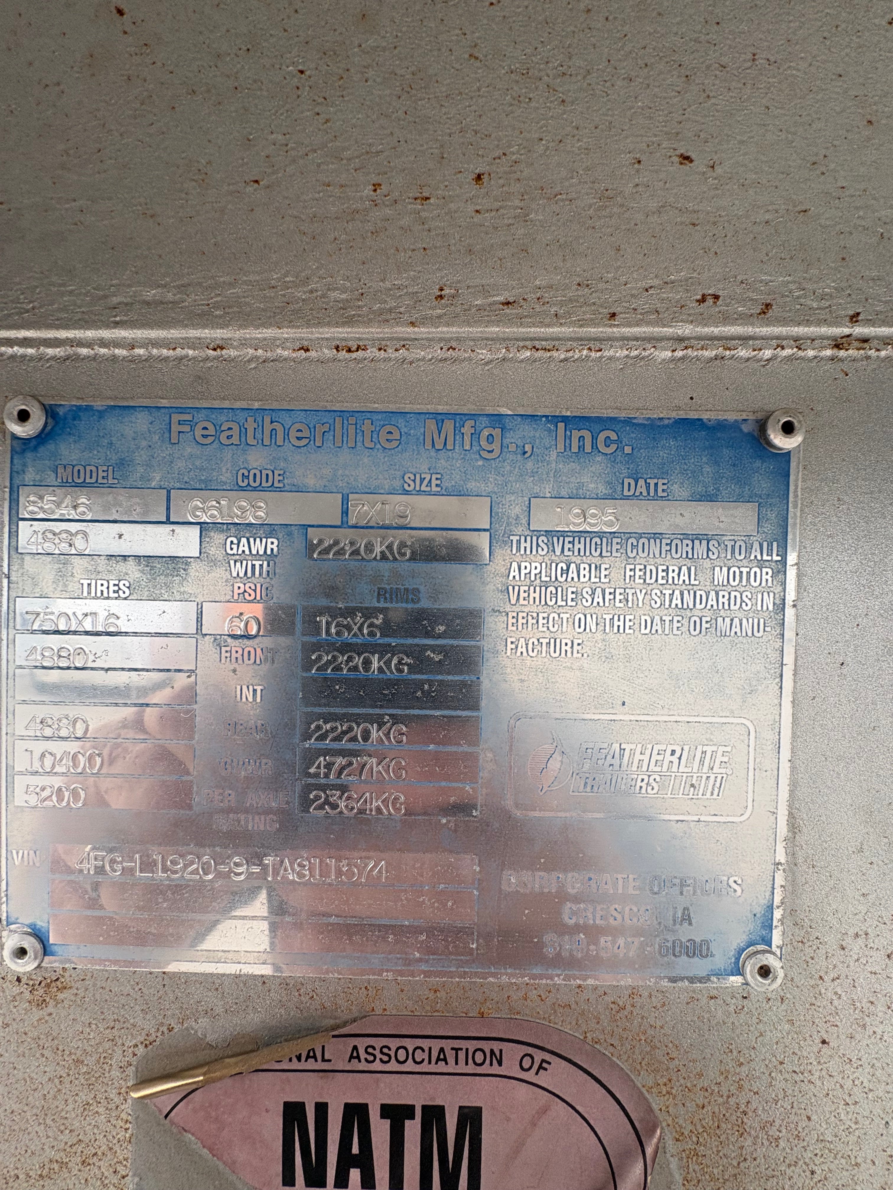 close up of Featherlite trailer manufacturer plate showing model number, VIN, size specifications, weight ratings and production details on aluminum data tag mounted inside trailer.