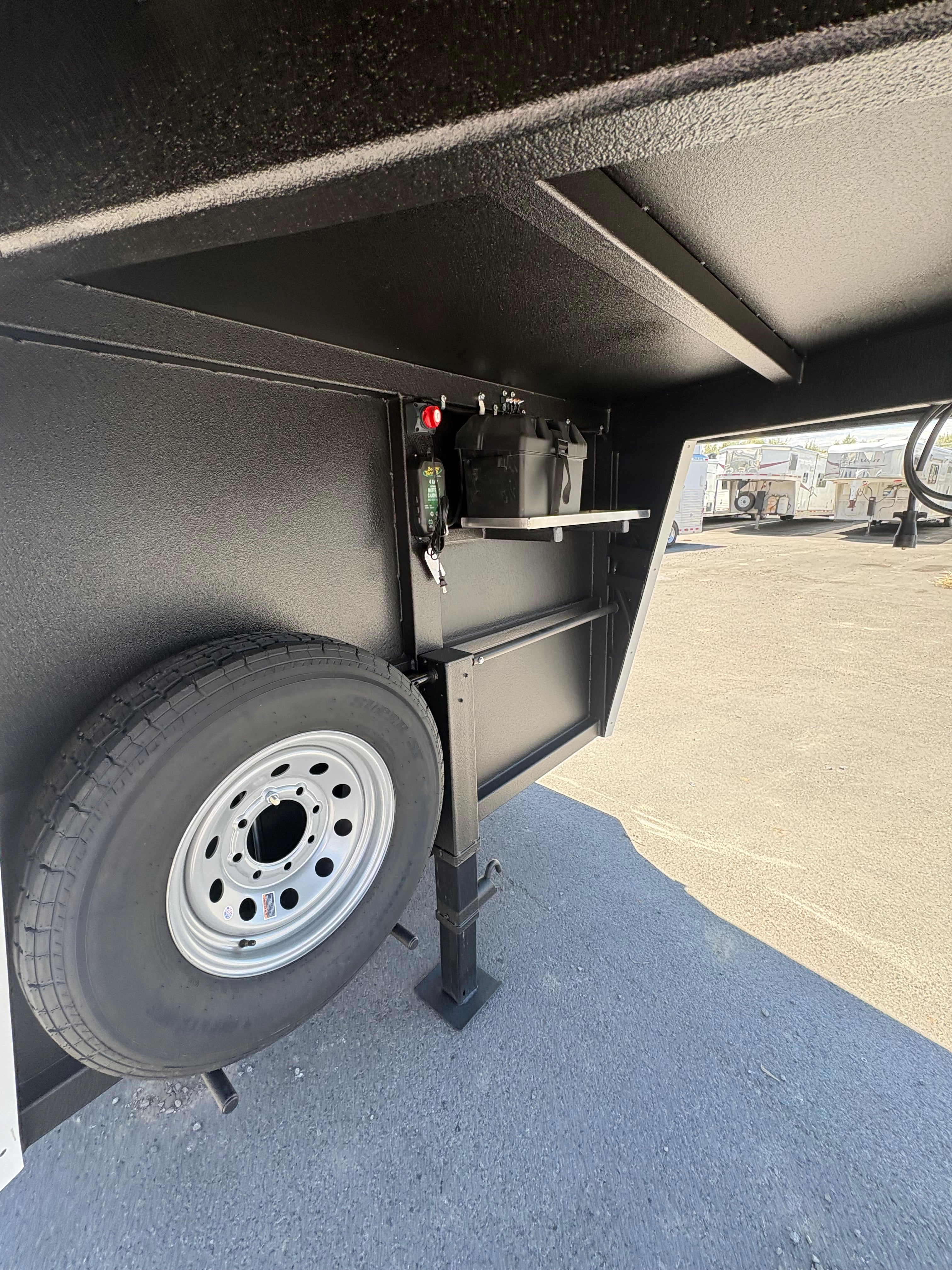 Gooseneck storage area of Logan Coach Bullseye XL trailer with spare tire and battery compartment.
