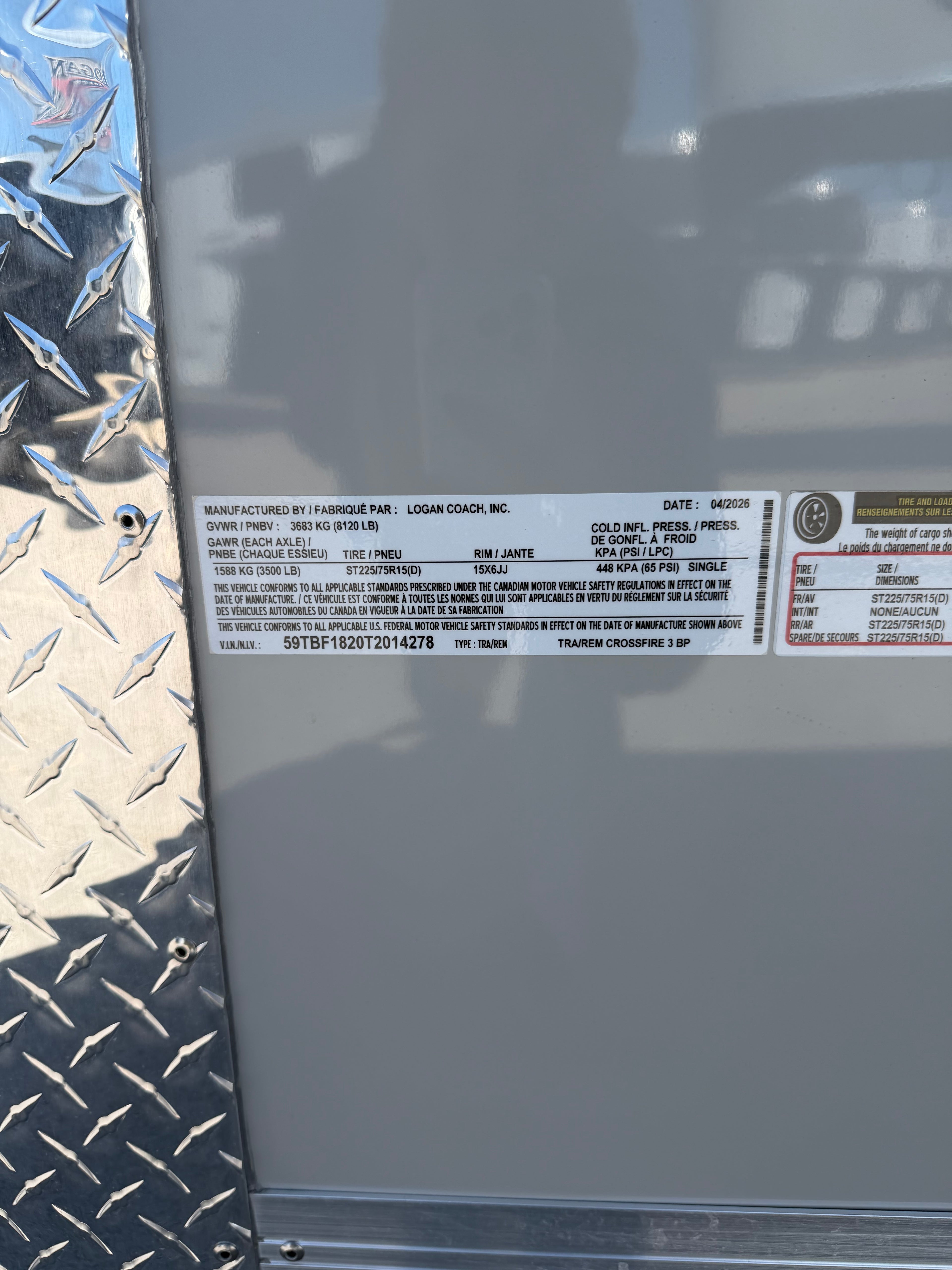 Close-up of a Logan Coach, Inc. trailer certification label dated 04/2026. Shows GVWR 3683 kg (8120 lb), GAWR 1588 kg (3500 lb), tire ST225/75R15(D), VIN 59TBF1820T2014278, and model TRAIREM CROSSFIRE 3 BP. Diamond plate visible on left.