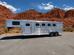 Logan Coach Bullseye XL 4 horse gooseneck trailer side view with aluminum body and horse windows in desert landscape.