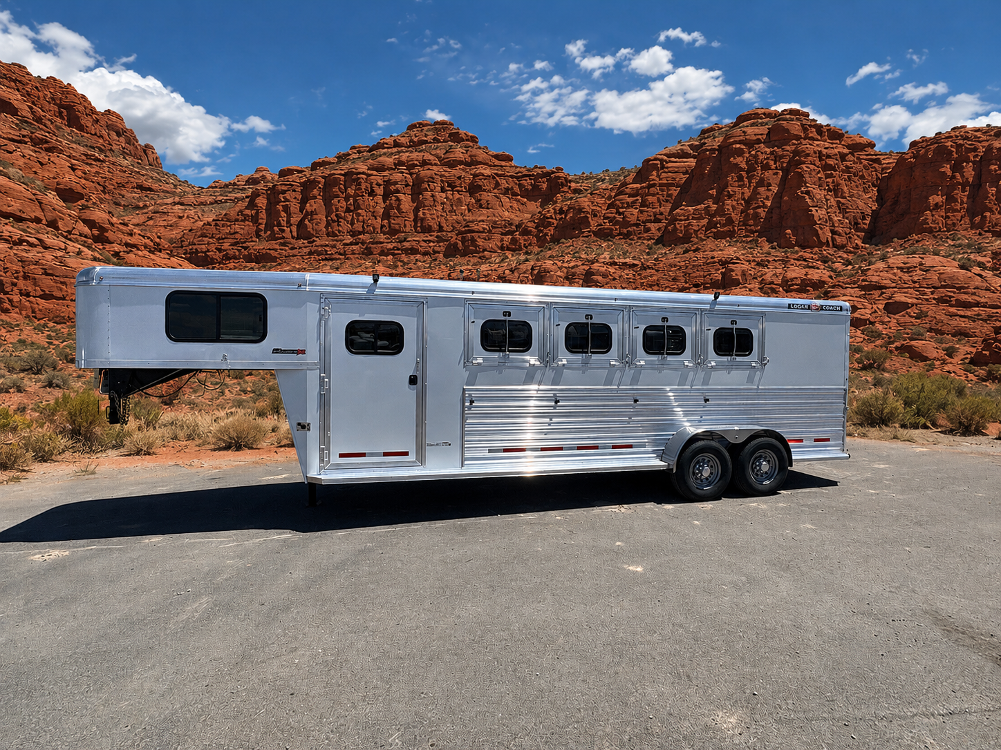 Logan Coach Bullseye XL 4 horse gooseneck trailer side view with aluminum body and horse windows in desert landscape.
