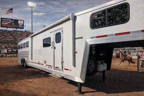 A horse trailer from Frontier Trailers & Roping Supply parked in front of a stadium, ready for an event.