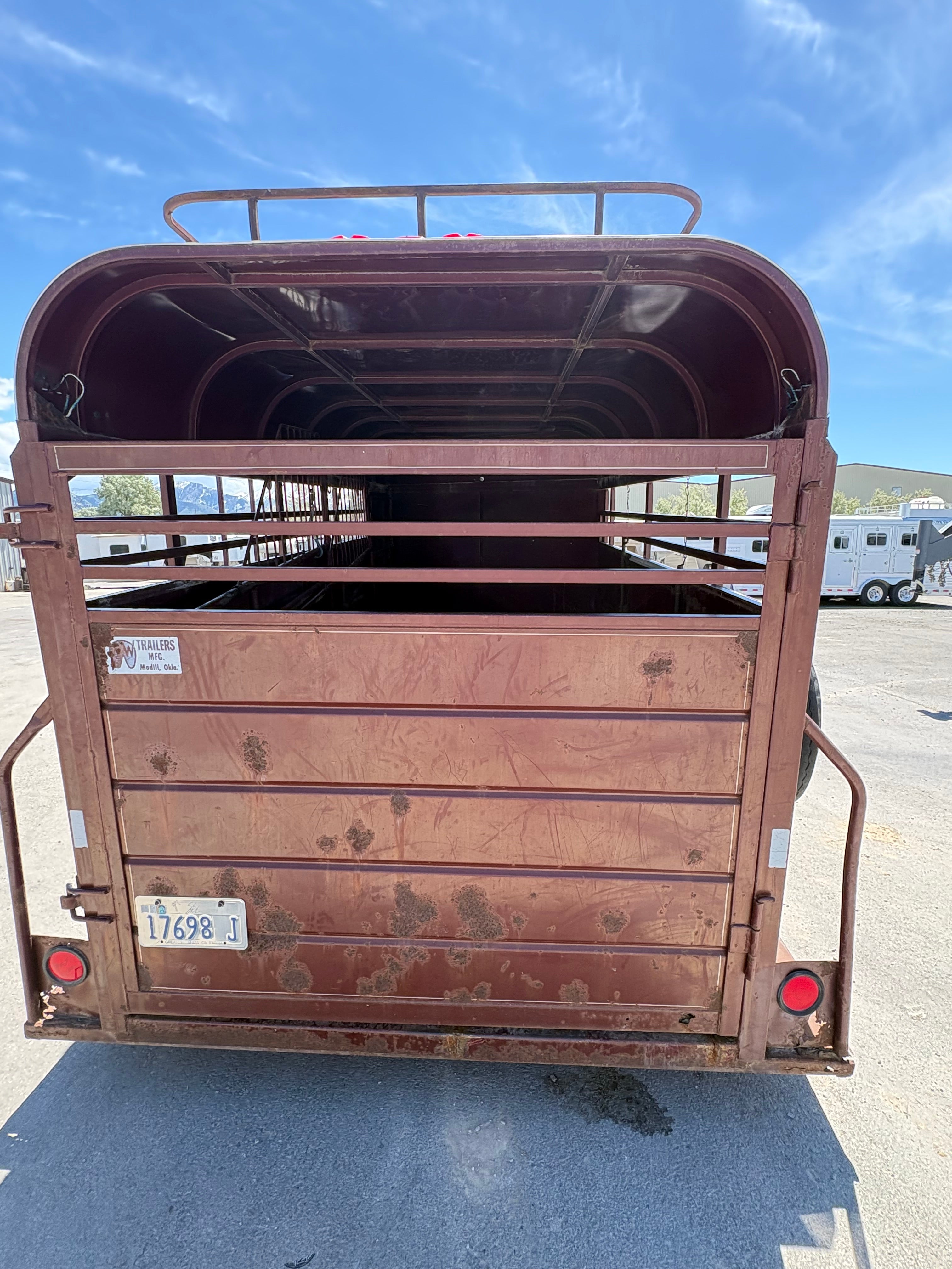 rear view of red horse trailer with steel slat gate, weathered paint, and round tail lights.