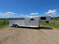 Logan Coach 26 stock combo gooseneck horse trailer side view with aluminum body, livestock vents and dual axles parked on ranch under blue sky