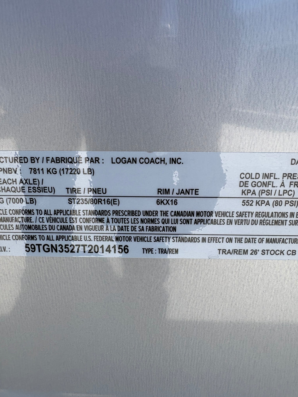 Logan Coach 26 stock combo trailer VIN and specification label showing GVWR, axle rating and tire details on aluminum livestock trailer.