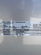 Logan Coach 26 stock combo trailer VIN and specification label showing GVWR, axle rating and tire details on aluminum livestock trailer.