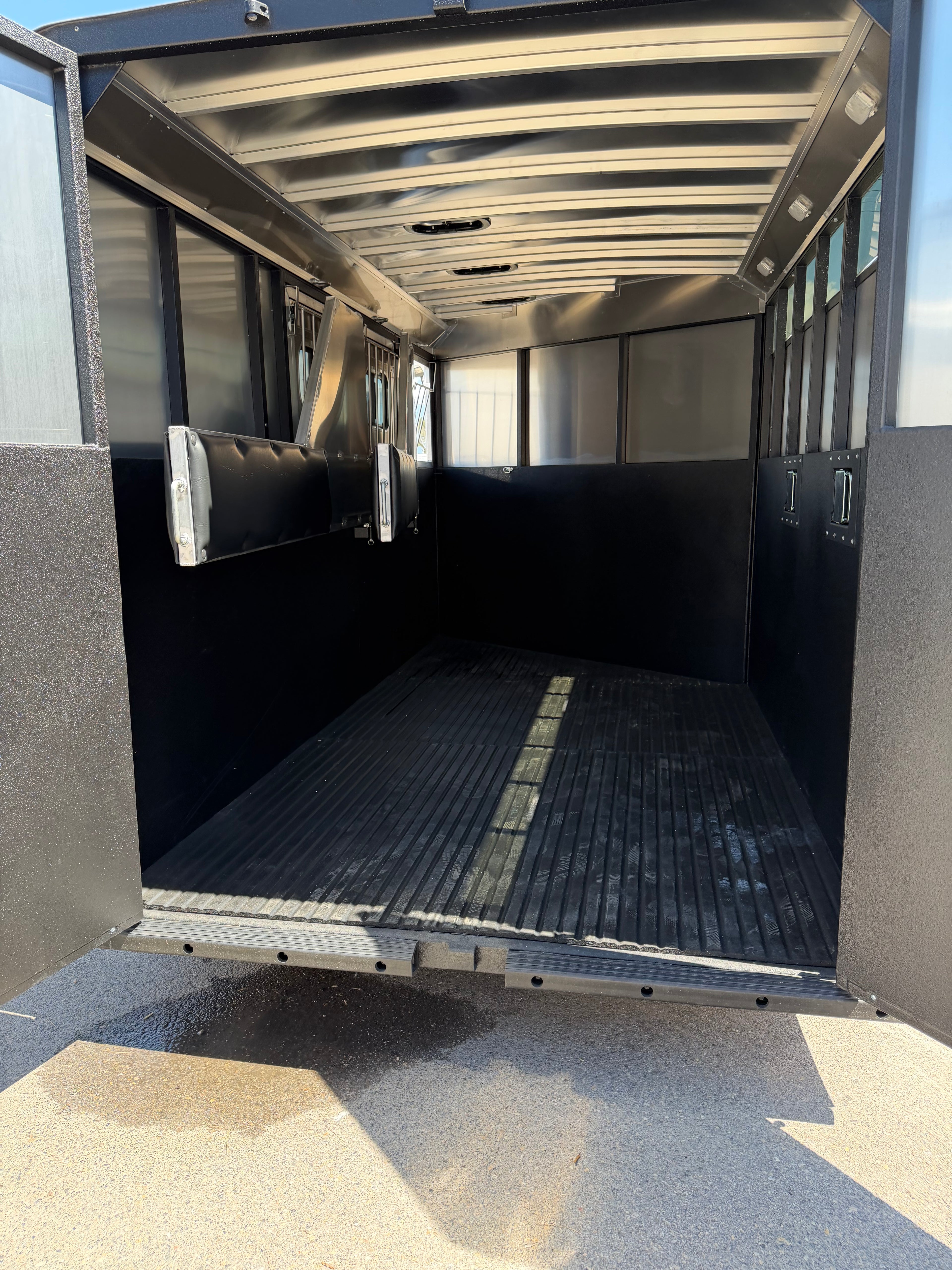 empty horse hauling area inside Logan Coach Crossfire bumper pull trailer with rubber floor mats, padded walls, roof vents, side windows, and open loading space designed for safe horse transportation.