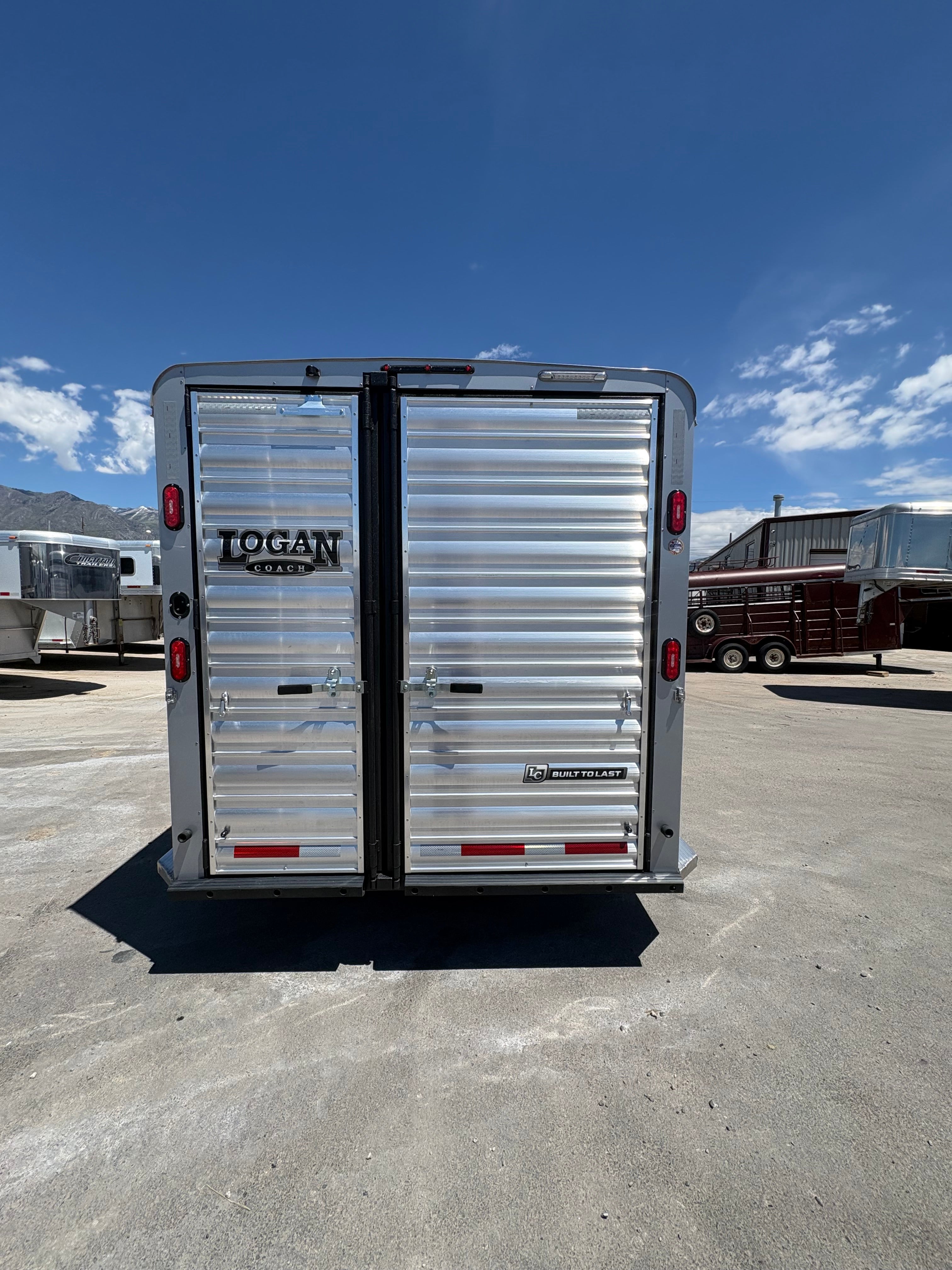 Logan Coach 26 stock combo trailer rear view with double doors, aluminum panels and latch hardware parked in trailer lot.