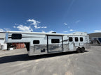 Living quarters horse trailer with gooseneck hitch and dual axles parked at facility, livestock trailer for ranch use.