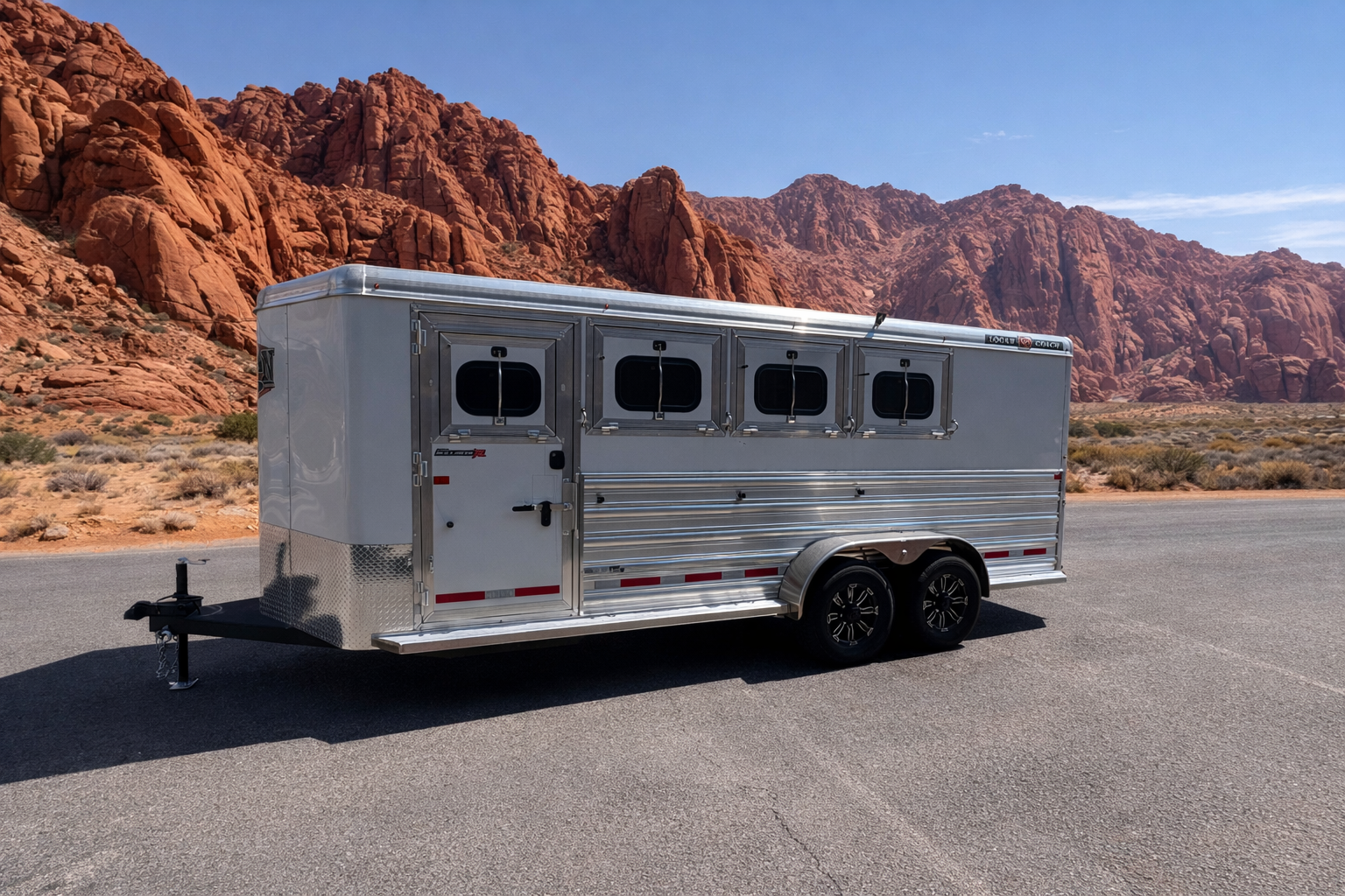 A horse trailer parked in front of a mountain, showcasing Frontier Trailers & Roping Supply branding.