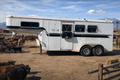 A horse trailer with a cow in the background, featuring the Frontier Trailers & Roping Supply logo.