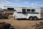 A horse trailer with a cow in the background, featuring the Frontier Trailers & Roping Supply logo.