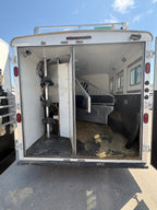 rear open horse compartment with saddle rack system, divider gates, rubber flooring, side windows, and spacious livestock area designed for safe horse transport inside trailer.