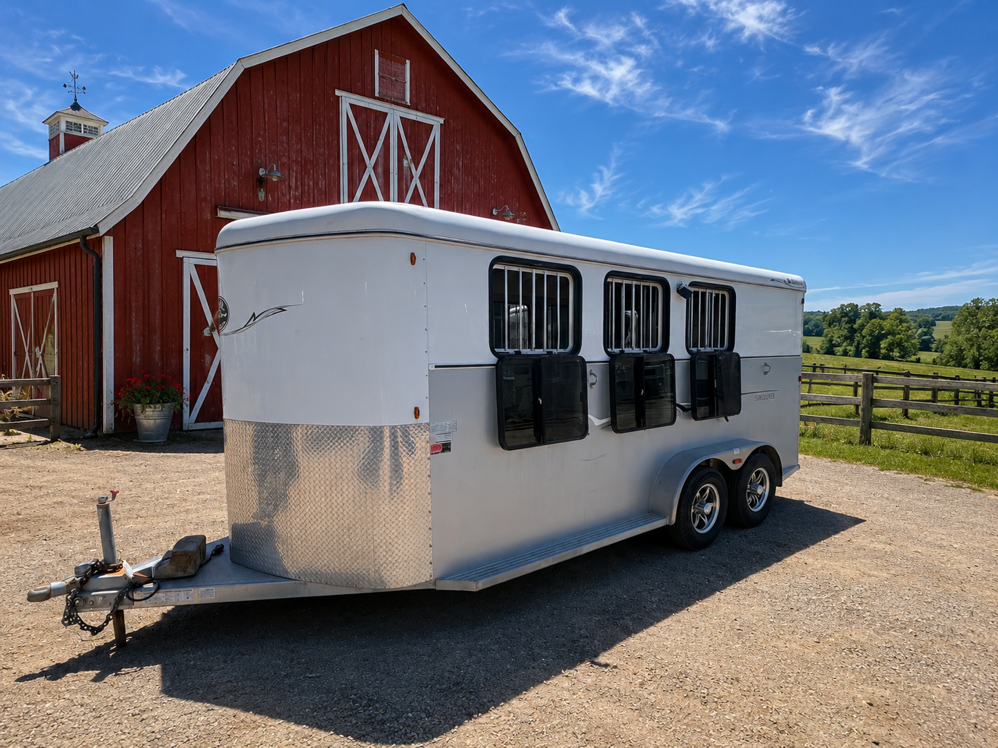 Royal T 3 horse bumper pull trailer front left side view with drop-down windows parked by red barn.