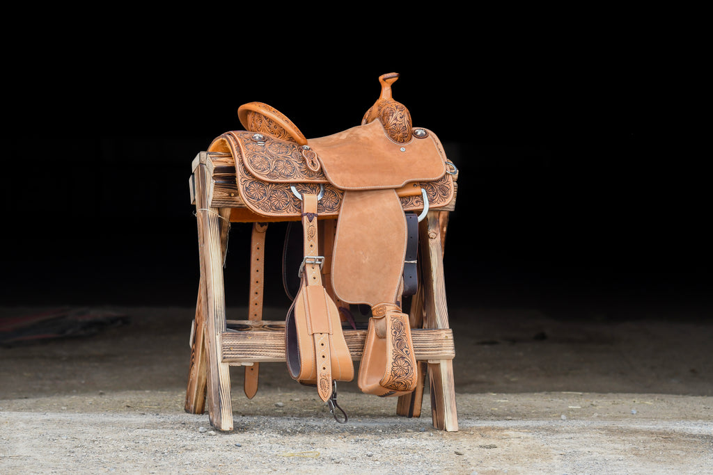 A saddle displayed on a wooden stand at Frontier Trailers & Roping Supply, showcasing equestrian gear.