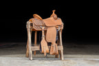A saddle displayed on a wooden stand at Frontier Trailers & Roping Supply, showcasing equestrian gear.