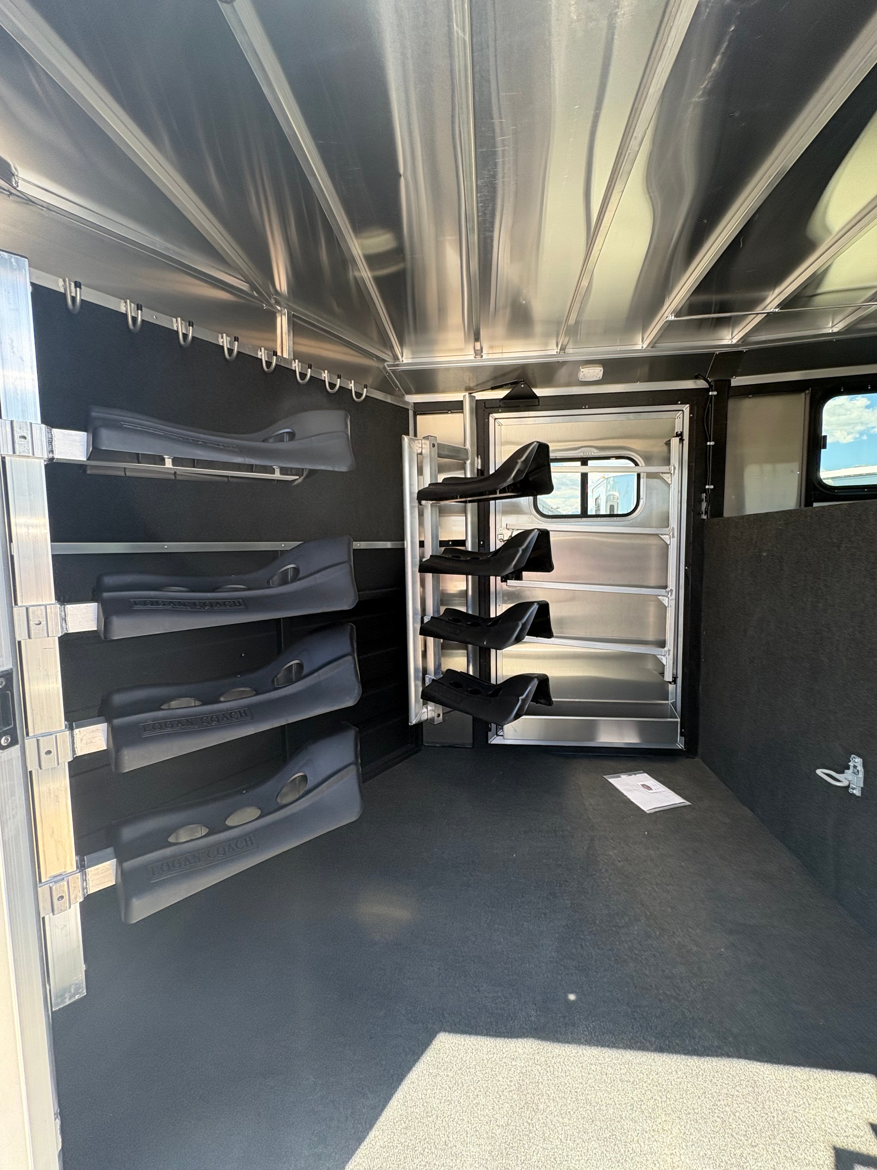 Logan Coach 26 stock combo trailer tack room interior with saddle racks, bridle hooks and storage compartments for ranch and rodeo use.