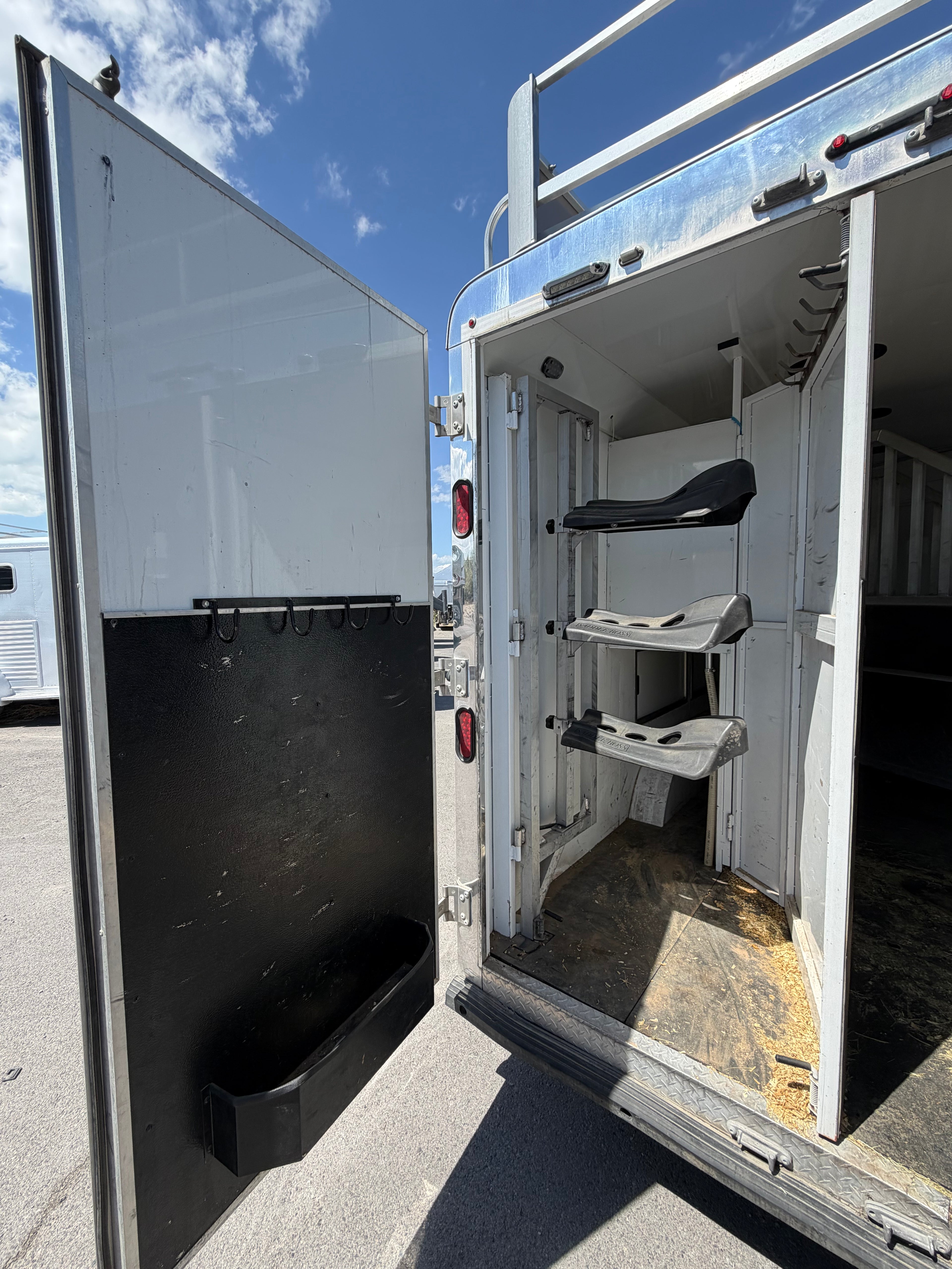 Horse trailer rear tack room with saddle racks and storage, livestock trailer gear compartment for ranch and rodeo use.