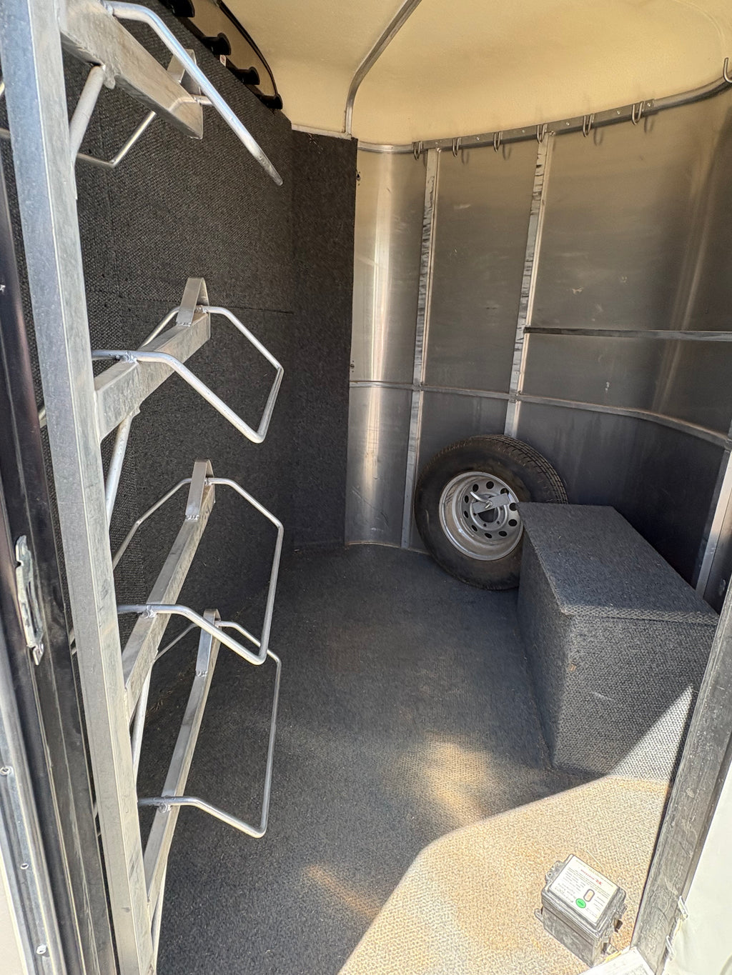 Interior tack room of 2013 Royal T 3 horse trailer with saddle racks and spare tire storage.