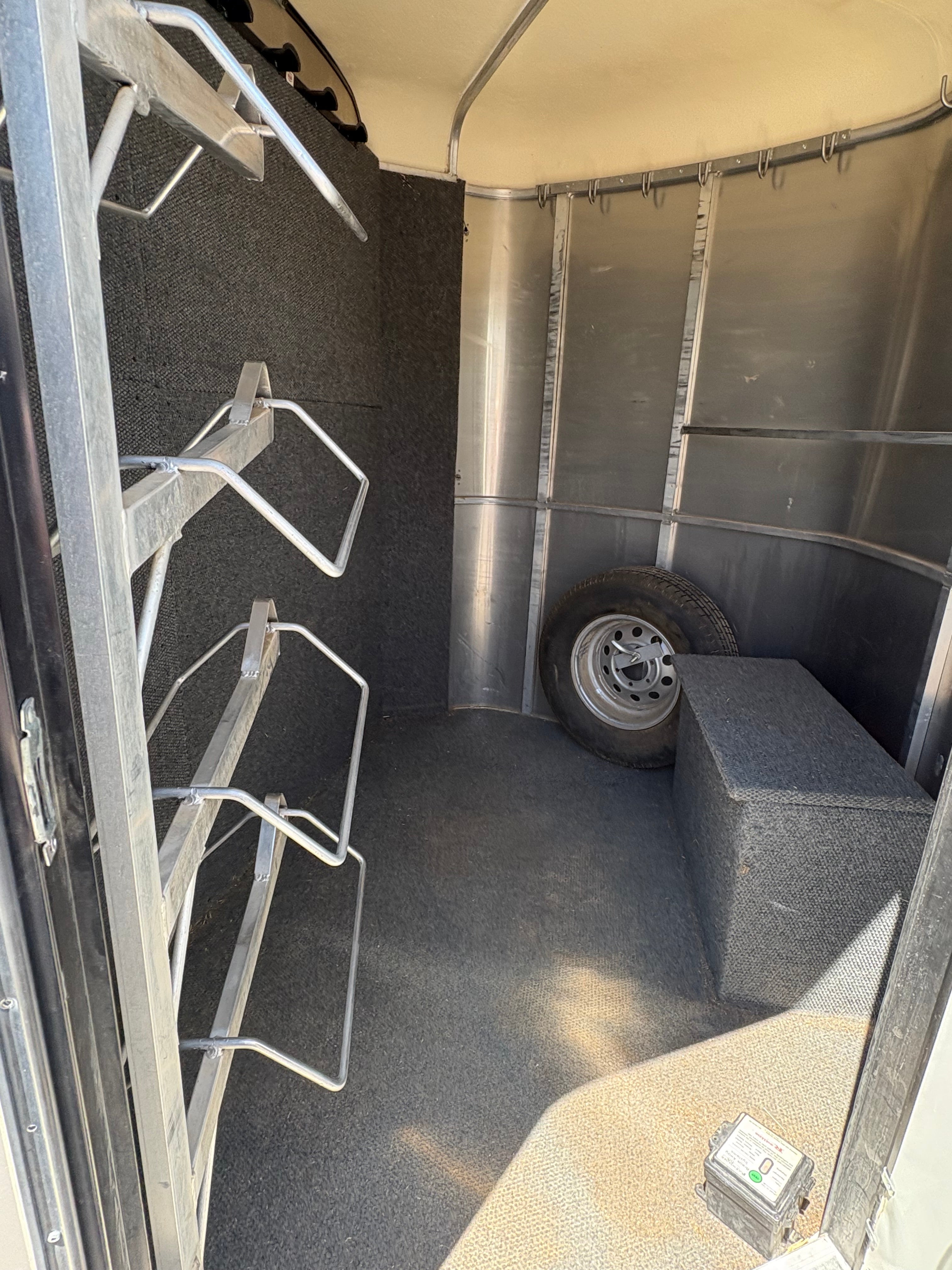 Interior tack room of 2013 Royal T 3 horse trailer with saddle racks and spare tire storage.